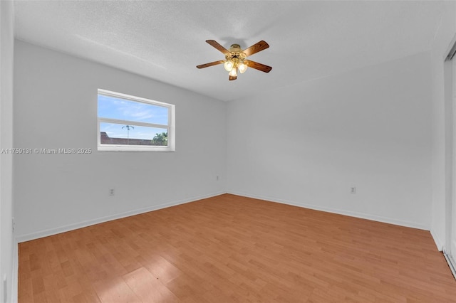 empty room with a ceiling fan, light wood-style floors, baseboards, and a textured ceiling