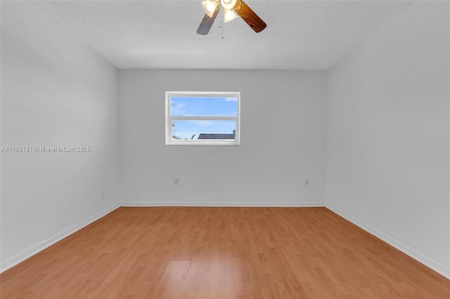 spare room featuring light wood-style flooring, a textured ceiling, baseboards, and a ceiling fan