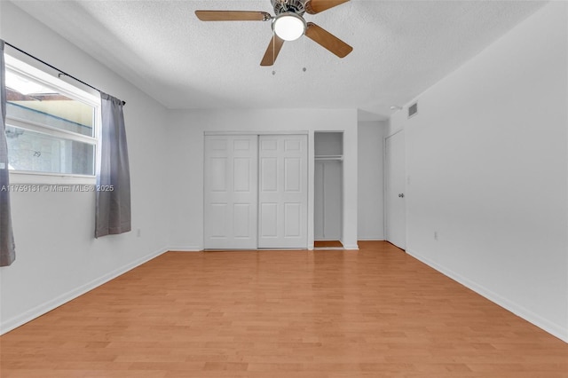 unfurnished bedroom with baseboards, visible vents, a textured ceiling, and light wood-style floors