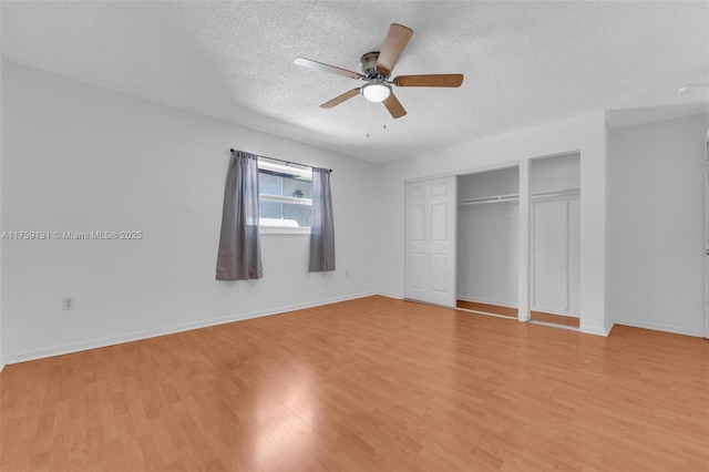 unfurnished bedroom featuring a closet, baseboards, a textured ceiling, and light wood-style floors