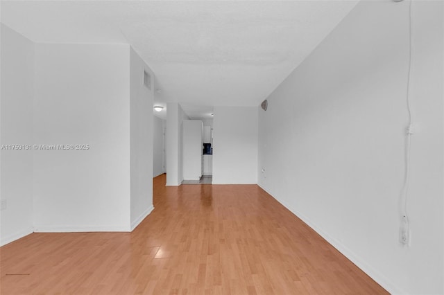 empty room featuring visible vents, baseboards, and light wood-style floors