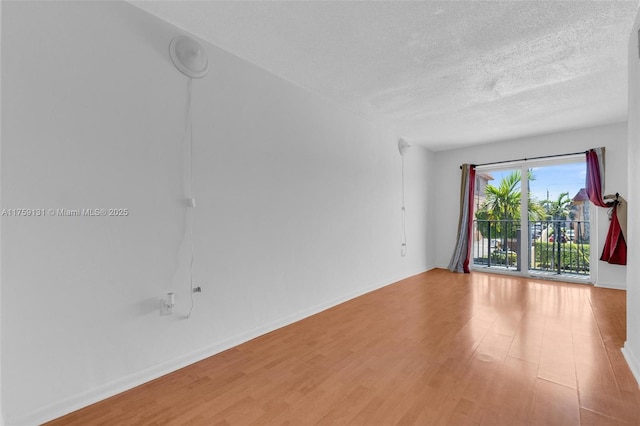 unfurnished room featuring baseboards, a textured ceiling, and wood finished floors