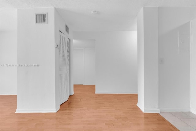 empty room featuring visible vents, baseboards, light wood-style floors, and a textured ceiling