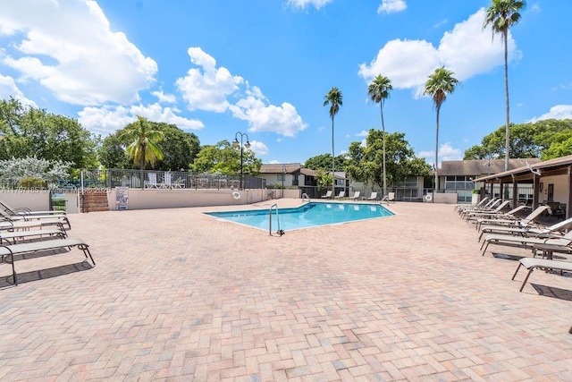 community pool with a patio area and fence