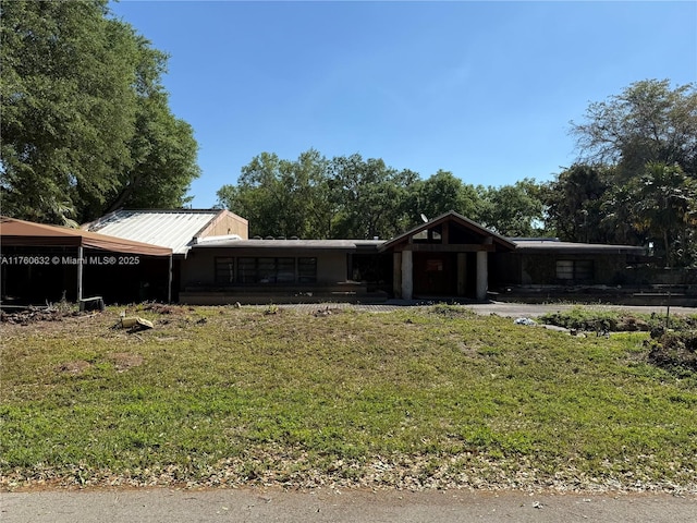 view of front of house with metal roof, a carport, and a front lawn