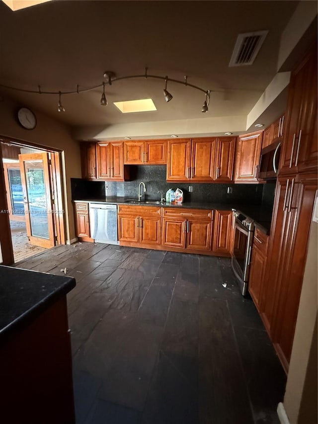 kitchen with dark countertops, visible vents, stainless steel appliances, and a sink