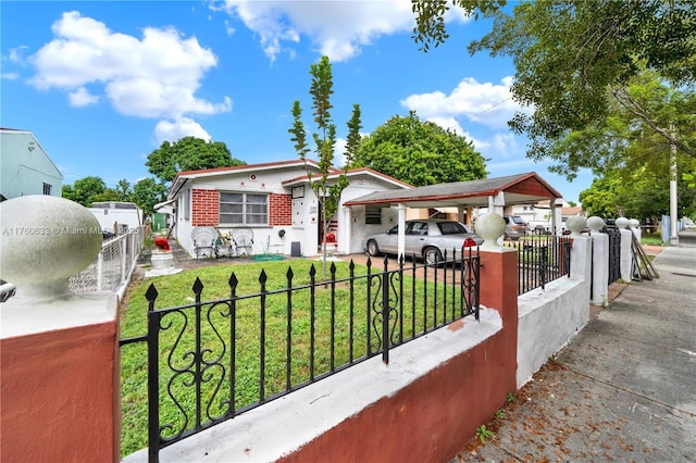 bungalow featuring a fenced front yard, brick siding, a front yard, and a carport