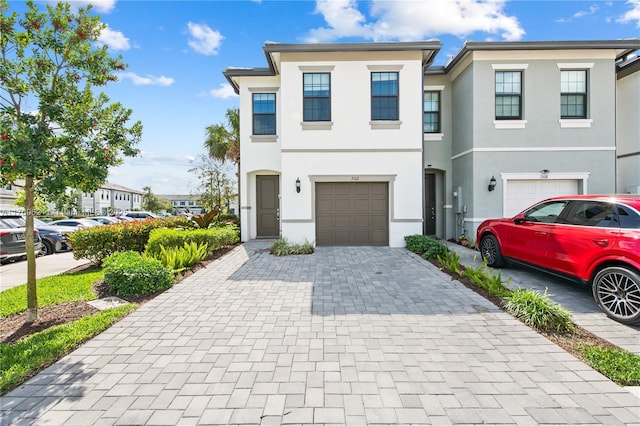 multi unit property with stucco siding, an attached garage, and decorative driveway