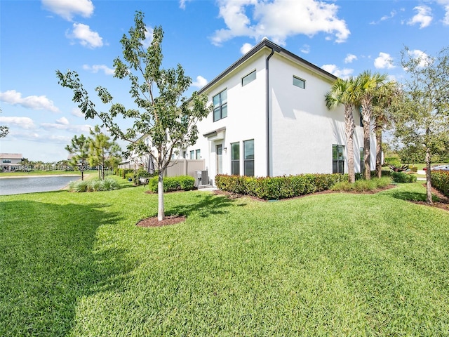 view of property exterior featuring stucco siding, a lawn, and a water view