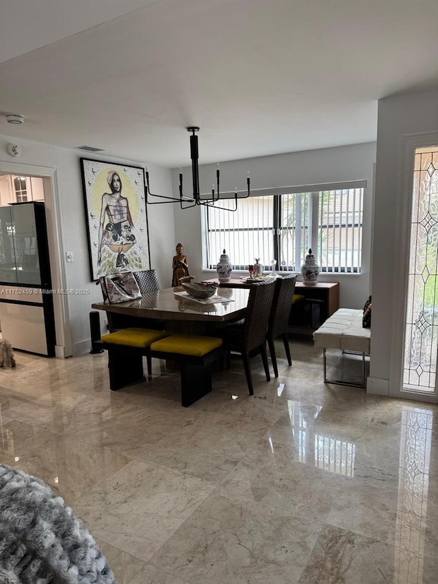 dining area featuring a notable chandelier and marble finish floor