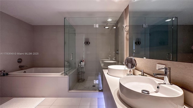 bathroom featuring tile patterned flooring, a shower stall, a garden tub, and a sink