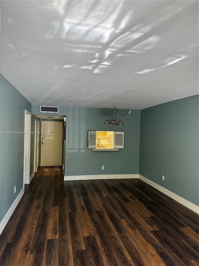 empty room with visible vents, dark wood-type flooring, and baseboards