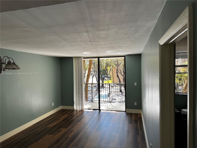 empty room featuring floor to ceiling windows, baseboards, and wood finished floors