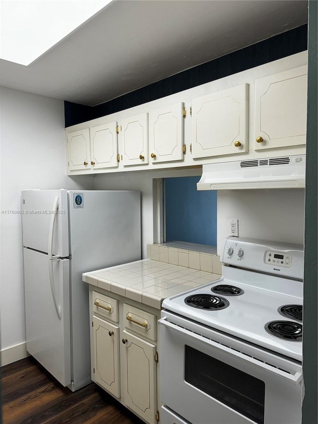 kitchen with white appliances, white cabinets, dark wood-style floors, and under cabinet range hood