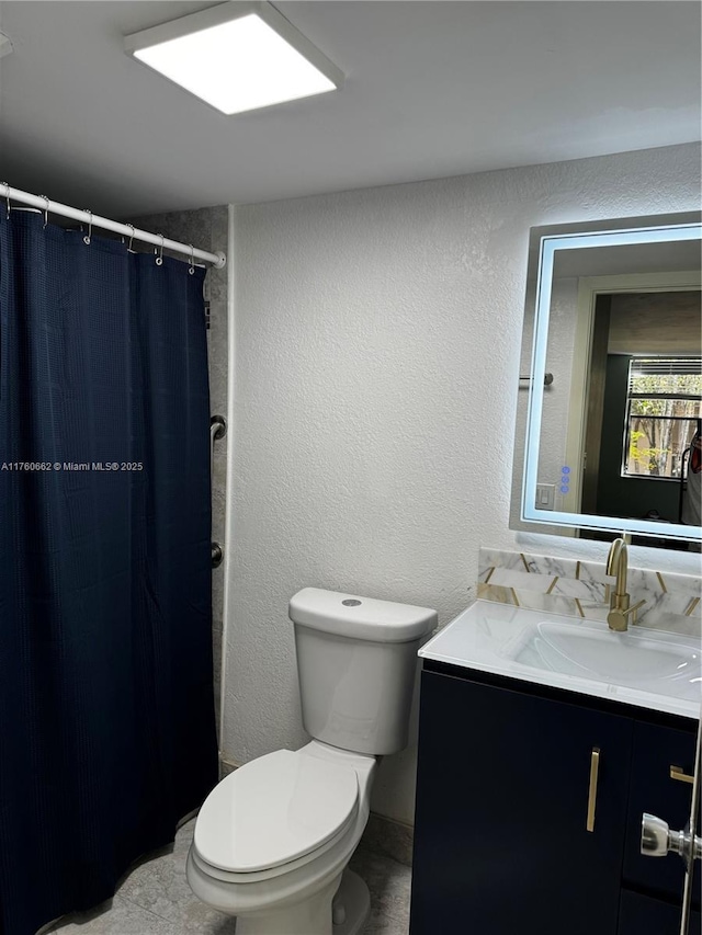 full bathroom featuring toilet, vanity, a shower with shower curtain, and a textured wall