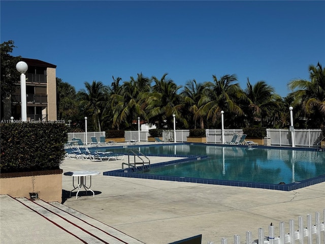 pool with a patio area and fence