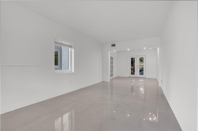 unfurnished living room with french doors, visible vents, and tile patterned flooring