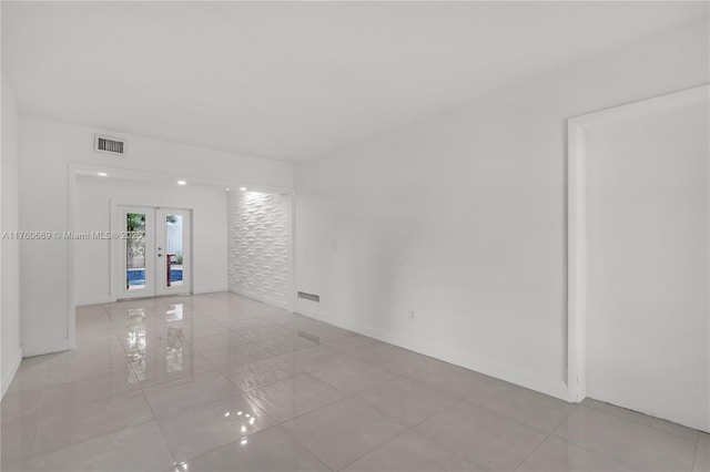 unfurnished room featuring tile patterned flooring, french doors, visible vents, and baseboards