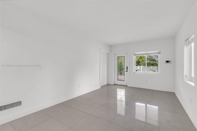 tiled spare room featuring visible vents and baseboards