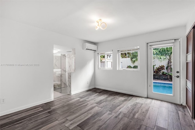 empty room featuring wood finished floors, baseboards, and a wall mounted AC