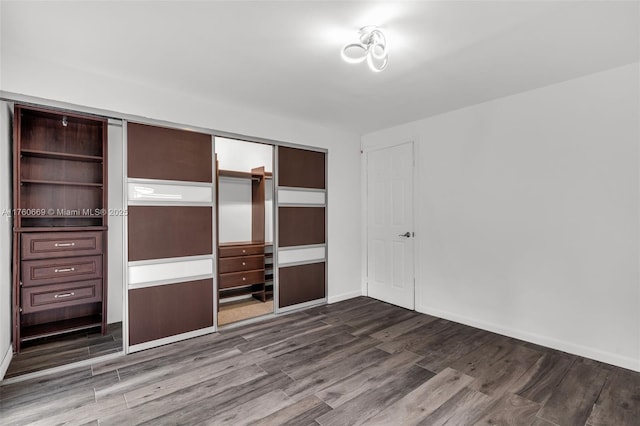 unfurnished bedroom with a closet, dark wood finished floors, and baseboards