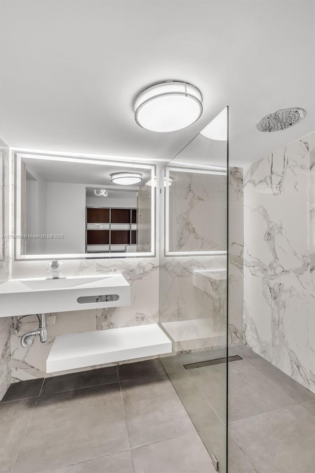 full bathroom featuring tile walls, a marble finish shower, and a sink