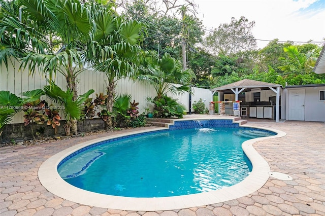 view of pool with outdoor dry bar, a patio, a fenced backyard, exterior kitchen, and a fenced in pool