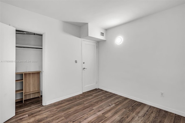 unfurnished bedroom with a closet, baseboards, visible vents, and wood finished floors