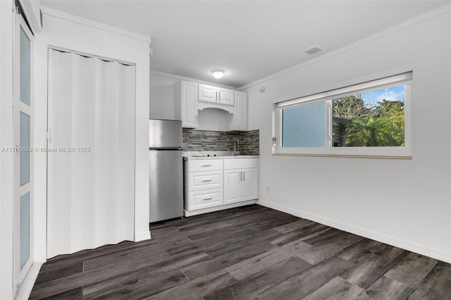 kitchen featuring visible vents, dark wood-style flooring, freestanding refrigerator, white cabinets, and backsplash