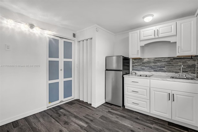 kitchen featuring freestanding refrigerator, a sink, dark wood-type flooring, white cabinets, and tasteful backsplash