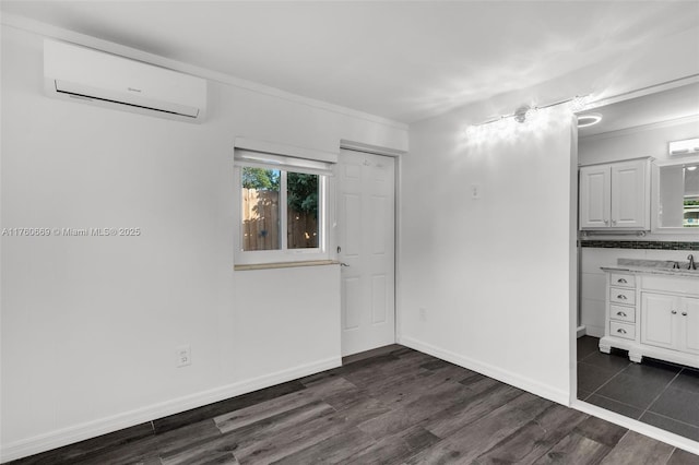 spare room with dark wood-style floors, a wall mounted air conditioner, baseboards, and a sink