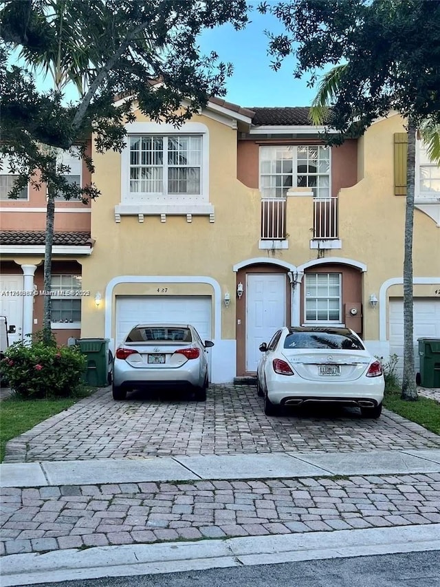 view of front facade with stucco siding, decorative driveway, and an attached garage