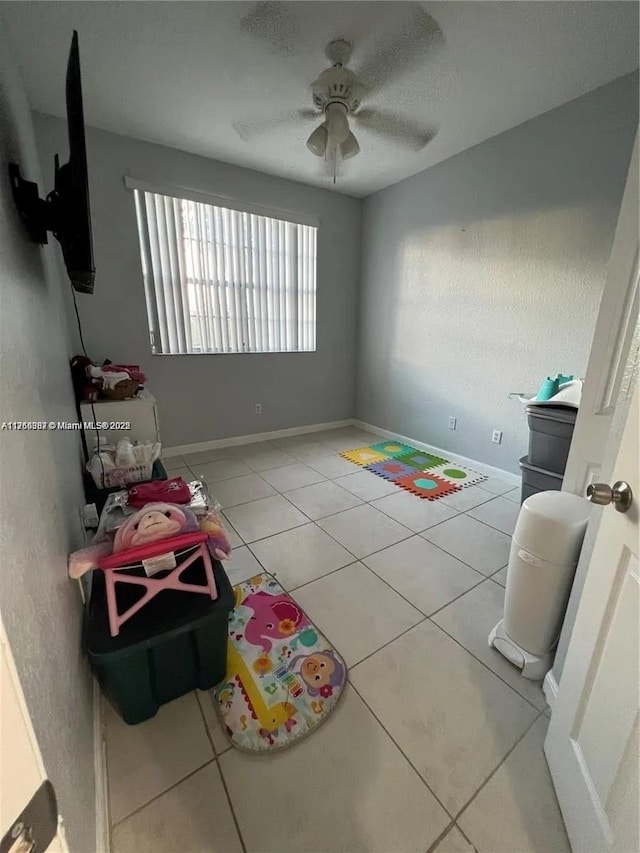 interior space with baseboards, light tile patterned flooring, and a ceiling fan