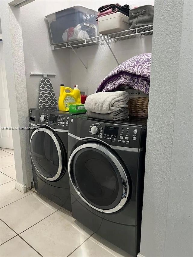 washroom with washer and clothes dryer, laundry area, tile patterned floors, and a textured wall