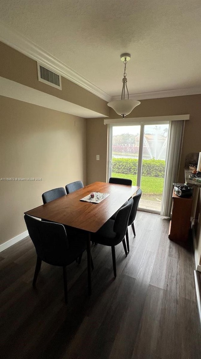 dining space with visible vents, baseboards, wood finished floors, and ornamental molding