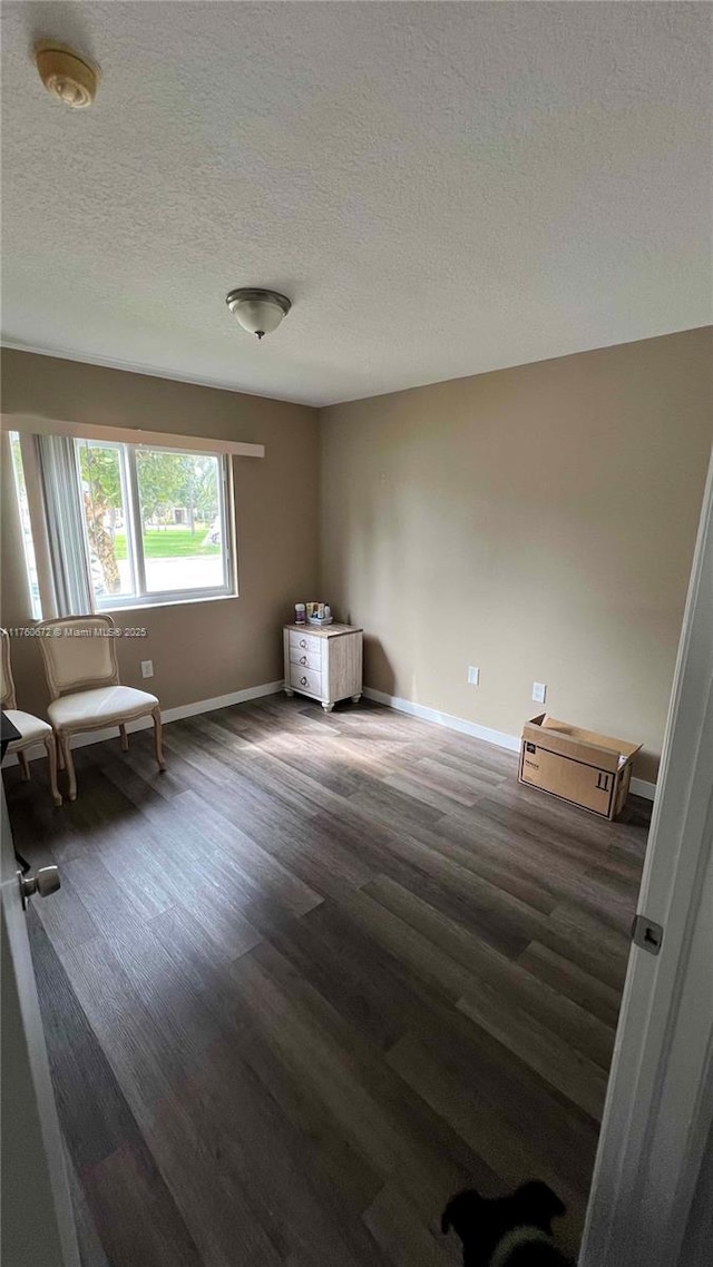 empty room featuring baseboards, a textured ceiling, and wood finished floors