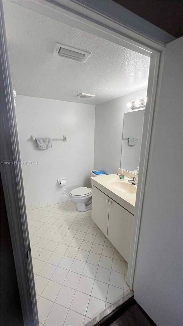 bathroom with vanity, tile patterned floors, toilet, and a textured ceiling