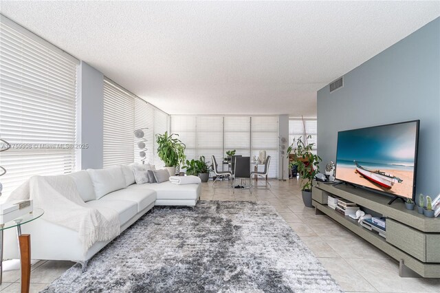 living area featuring light tile patterned floors, visible vents, and a textured ceiling