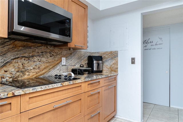 200 Leslie Dr Unit 430, Hallandale Beach, FL 33009 - kitchen featuring stainless steel microwave, backsplash, light tile patterned floors, light stone countertops, and black electric cooktop