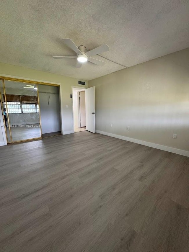 unfurnished bedroom with wood finished floors, visible vents, and baseboards