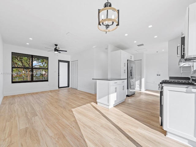 kitchen with dark countertops, light wood-type flooring, recessed lighting, stainless steel appliances, and white cabinetry