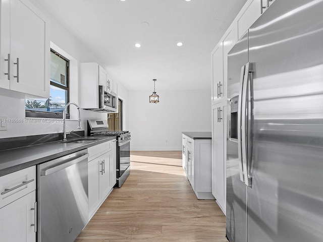 kitchen featuring white cabinetry, dark countertops, appliances with stainless steel finishes, and a sink