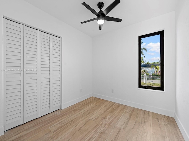 unfurnished bedroom featuring a closet, a ceiling fan, light wood-type flooring, and baseboards