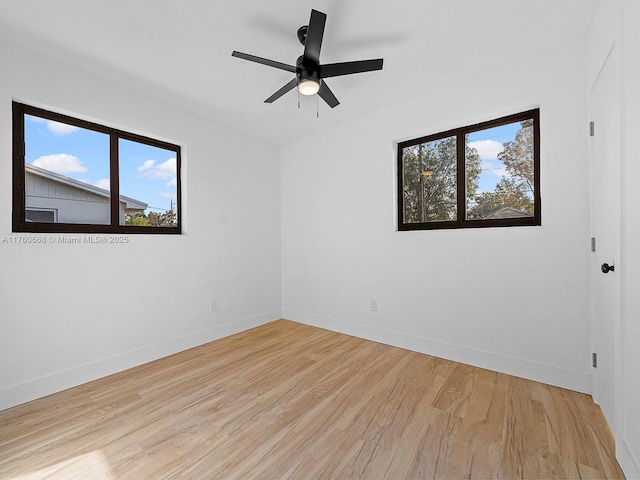 spare room with wood finished floors, baseboards, a wealth of natural light, and ceiling fan