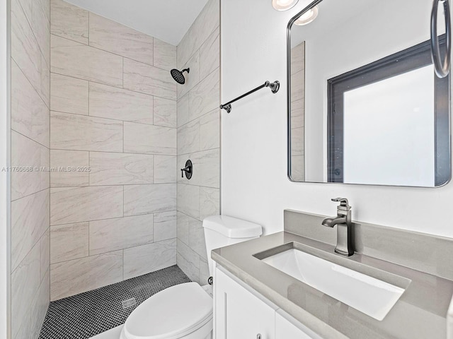 full bath featuring a tile shower, toilet, and vanity