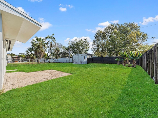 view of yard featuring a storage shed, a fenced backyard, and an outdoor structure