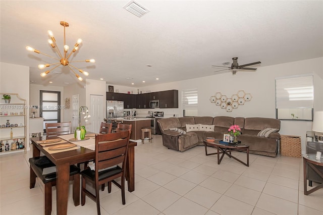 dining space with light tile patterned floors, ceiling fan with notable chandelier, visible vents, and a healthy amount of sunlight