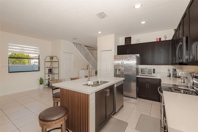 kitchen with visible vents, a breakfast bar, a sink, appliances with stainless steel finishes, and light tile patterned floors