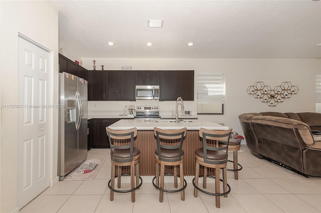 kitchen with visible vents, a sink, open floor plan, appliances with stainless steel finishes, and light countertops