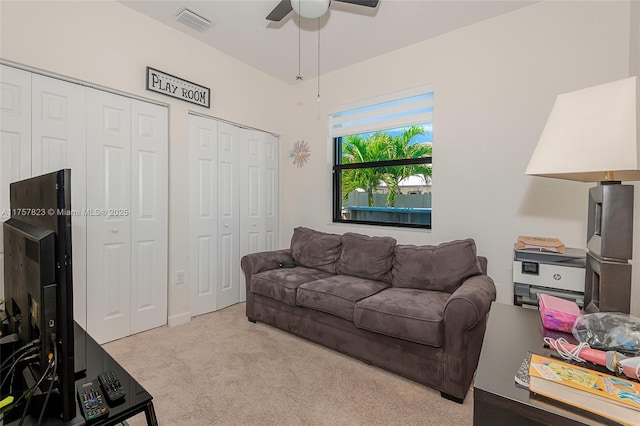 living room with visible vents, carpet floors, and a ceiling fan